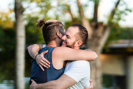 Men embracing while smiling in a parkの写真素材