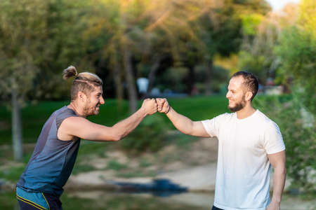 Two men clashing fists in a parkの写真素材