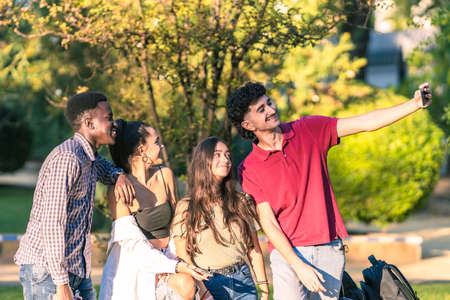 Group of multiethnic young people taking a selfie with a mobile in a park