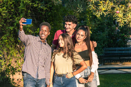 Group of multiethnic friends taking a selfie with a mobil standing in a park