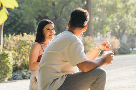 Profile of a young couple sitting on a park drinking soft drink in summerの写真素材