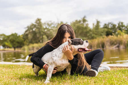 Young female kissing a dog while sitting next to a river