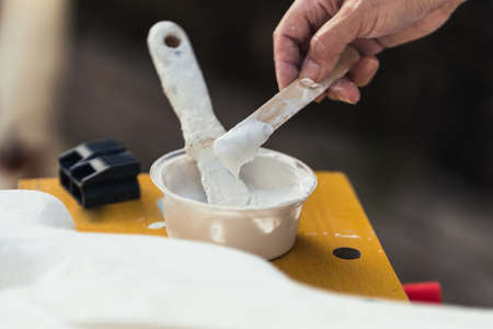 Person dipping white paste with a spatula in a workshopの写真素材