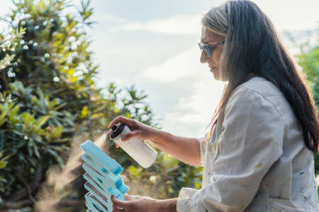 Woman painting polystyrene letters with paint on spray outdoors