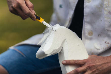 Person shaping a piece of polystyrene to create the figure of an animalの写真素材