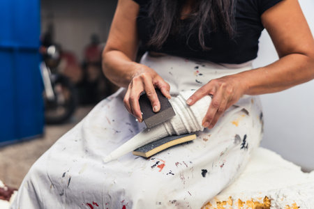 Woman filing by hand a polystyrene sculpture in a garden