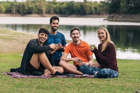 Sportive people facing the camera while drinking tea sitting on a parkの写真素材