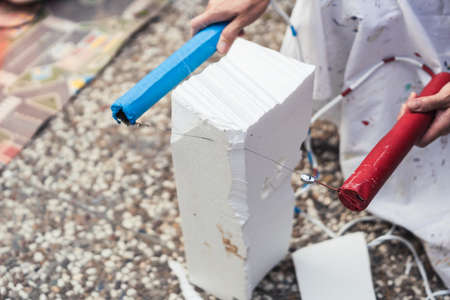 Woman chopping a block of polystyrene with a hot steel cable outdoorsの写真素材