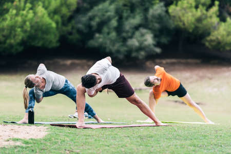 Group of people practising yoga on a parkの写真素材