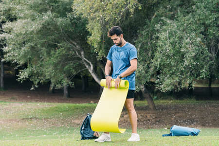 Sportive male rolling out a yoga mat in a forestの写真素材