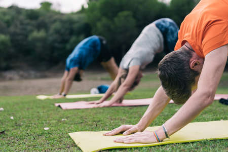 Three man doing yoga in a parkの写真素材