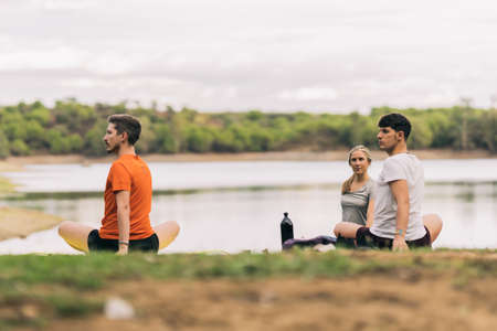 People stretching while doing yoga in a park next to a lakeの写真素材