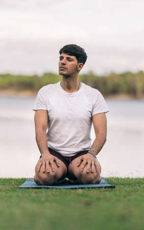 Sportive man sitting on a yoga mat with relaxed expression in a parkの写真素材