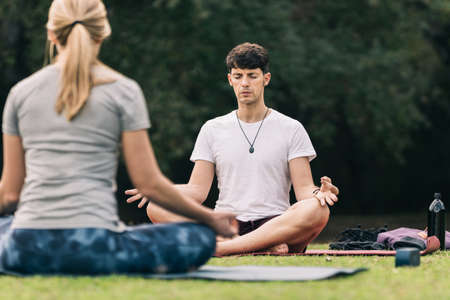 Man doing yoga above a mat in front of an instructor outdoorsの写真素材