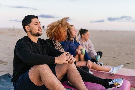 People sitting on mats on the beach drinking tea during the sunsetの写真素材