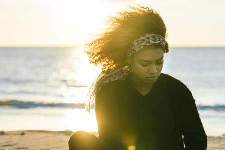 Sunlight illuminating a pregnant woman sitting on a beach after a yoga session