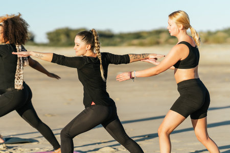 Yoga coach correcting the pose of a woman during a yoga class on a beachの写真素材