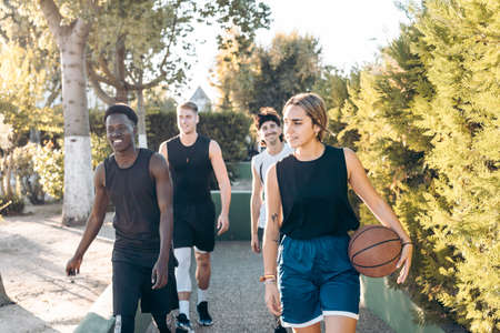 Four friends walking to a path with a basketball ballの写真素材