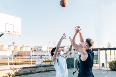 Three people jumping to catch the ball during a kick-off in a basketball match outdoors