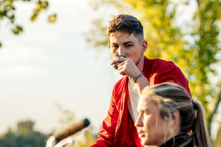 Man drinking tea form a thermo next to t woman in a parkの写真素材