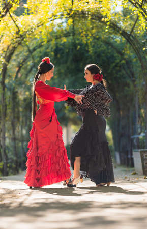 Two women in flamenco dresses dancing surrounded by an arch of plantsの写真素材