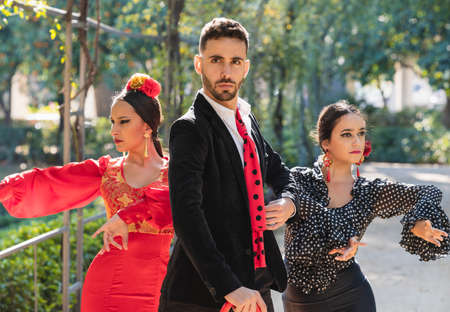 Three people in flamenco traditional dress dancing flamenco outdoorsの写真素材
