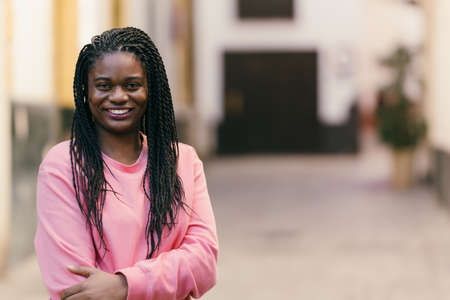 Portrait of a smiling adult african woman with braided hair in a pink jerseyの写真素材