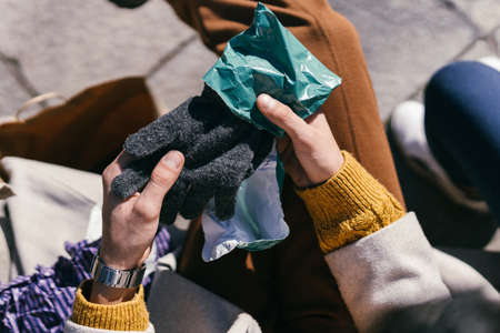 Man holding a pair of woolen gloves he has just been given sitting on a benchの写真素材