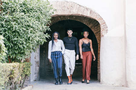 Three models walk through the archway of a building