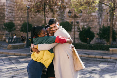Three friends hugging each other emotionally outdoorsの写真素材