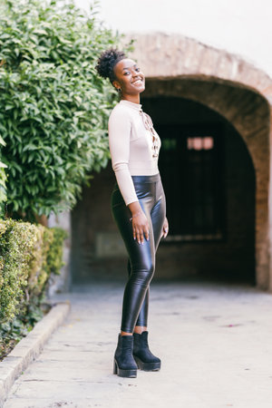 Sensual smiling african woman in black leggings standing outdoorsの写真素材