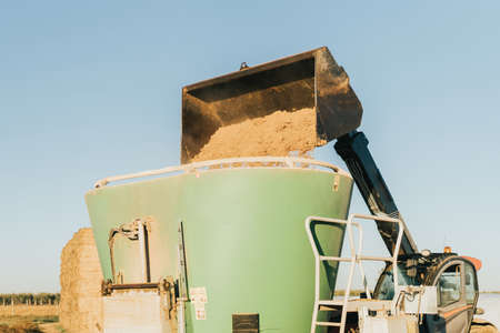 A tractor tipping animal feed inside containerの写真素材