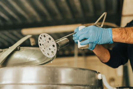 a mans hands collecting a milk sample for testing