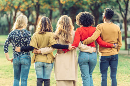 rear view of friends embracing in a parkの写真素材