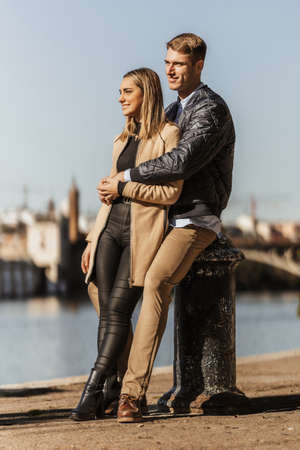 a couple embracing and leaning on a port bollardの写真素材