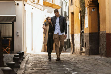 A young man puts his arm around his girlfriend as they walk through the streets of an ancient city.の写真素材