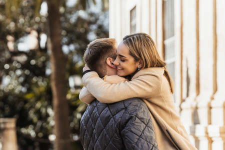 a smiling young woman hugs her boyfriend intenselyの写真素材
