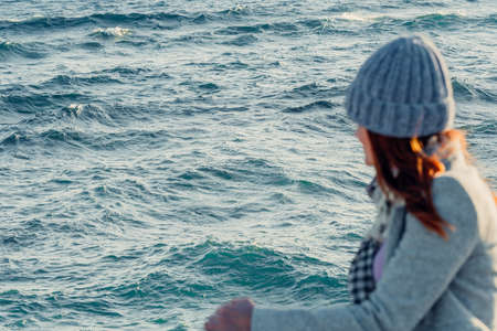 unrecognisable out-of-focus woman looks out to sea with rippled wavesの写真素材