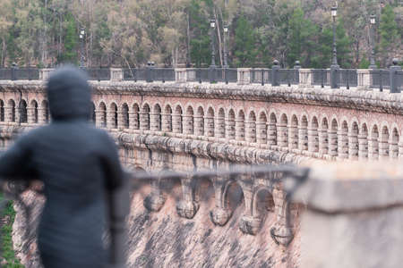 person in a jacket with a hood looks at a dam built at the beginning of the 20th century.の写真素材
