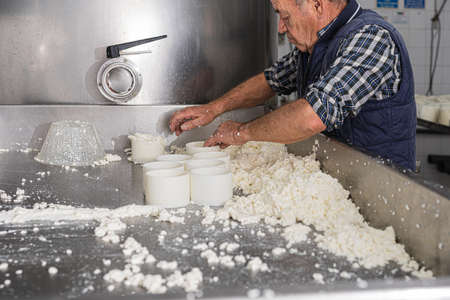 older man working in a fresh cheese factory