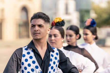 pose of a male flamenco student in a polka-dotted waistcoat in front of his female classmatesの写真素材