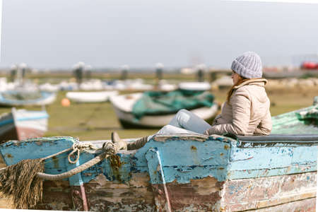woman in winter clothes sitting on a fishing boatの写真素材