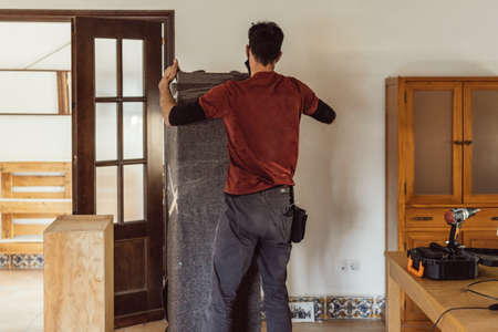 moving worker packing a piece of furniture with a blanketの写真素材