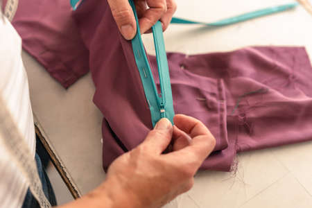 seamstress testing the operation of a zipper in her sewing shopの写真素材