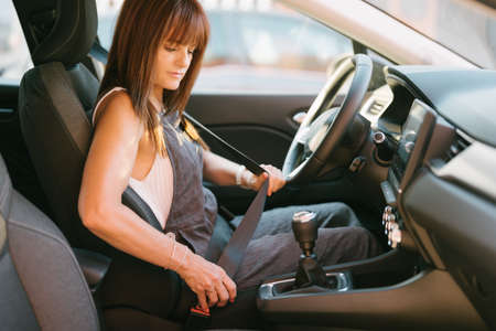 woman putting on her seat belt for securityの写真素材