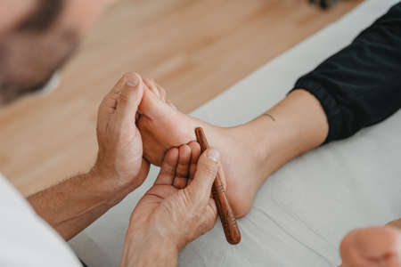 massaging the foot with a wooden stickの写真素材