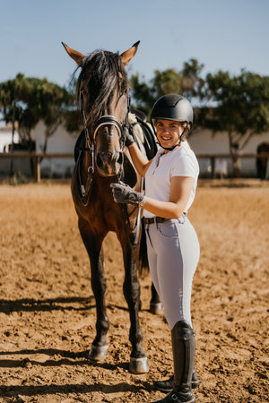 young woman in equestrian dressage clothes posing with her horse in the riding arena.の写真素材