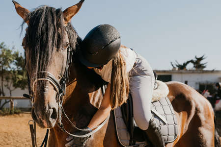 young woman in uniform and on her horse embraces him affectionatelyの写真素材
