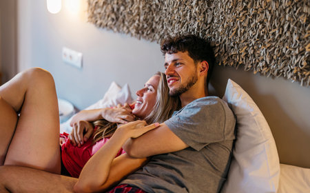 multiracial couple cuddling in bed on vacationの写真素材