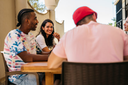 a brown-haired girl smiles and looks at an African-American friend while they are having lunchの写真素材